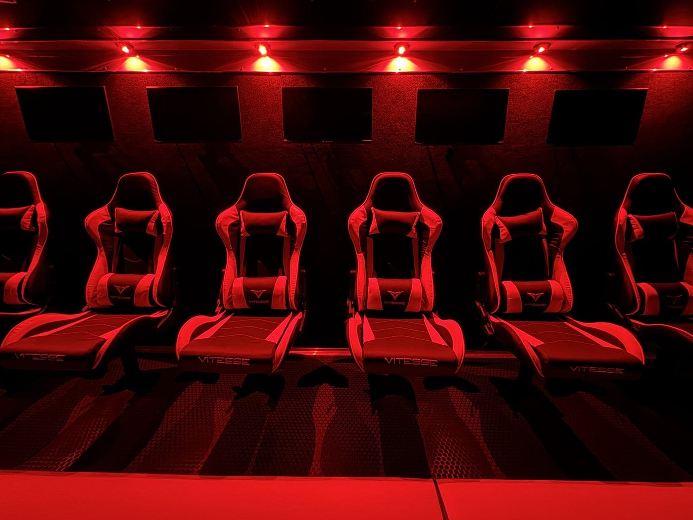 Inside a Next Level Gaming theater in the DMV, red LED lighting and gamer chairs